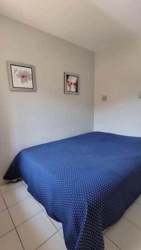 - un lit bleu dans une chambre blanche avec deux photos sur le mur dans l'établissement Cap Esterel le hameau au calme sans vis à vis vue mer terrasse couverte 2ème et dernier étage minimum de 7 nuitées, à Agay