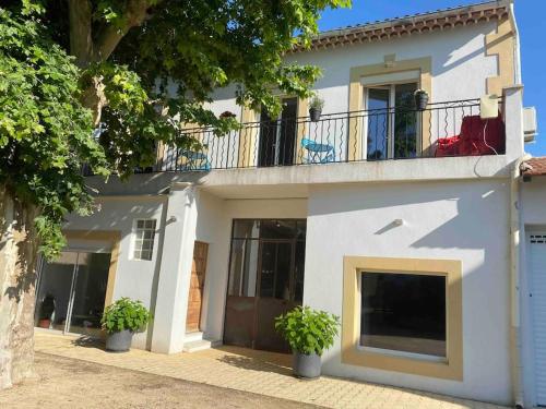 a white house with a balcony and two potted plants at Location appartement 1 chambre et dépendance en supplément voir infos importantes dans un mas provençal au coeur du luberon in Cavaillon