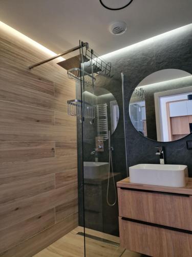 a bathroom with a sink and a shower with a mirror at Apartamenty przy plaży Shellter in Rogowo