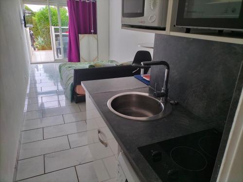 une cuisine avec un évier et un salon dans l'établissement PORT NATURE 2 Village Naturiste, au Cap d'Agde