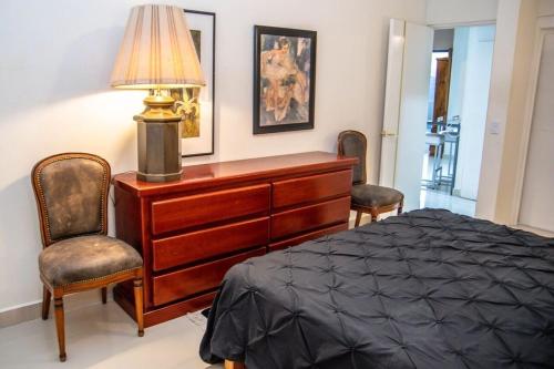 a bedroom with a bed and a dresser and two chairs at Casa Lana Central in Ajijic