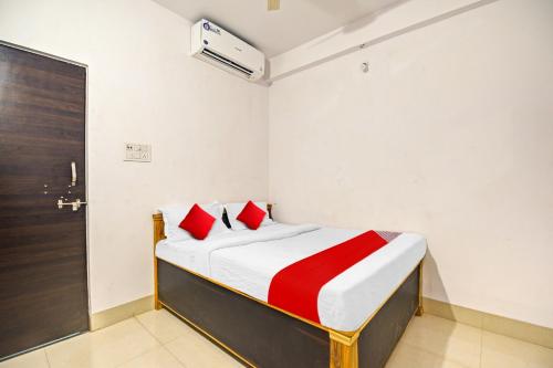 a bedroom with a bed with red pillows and a door at OYO Flagship 81047 Hotel Dream Inn in Gamhāria