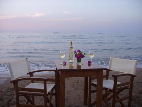a table with wine glasses and flowers on the beach at Talgo Suites in Stalida