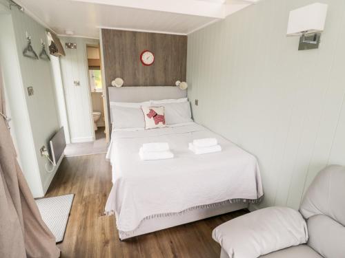 a bedroom with a large white bed with a clock on the wall at Hydrangea in Evesham