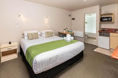 1 Schlafzimmer mit einem großen Bett und einer Küche in der Unterkunft Bella Vista Motel Greymouth in Greymouth