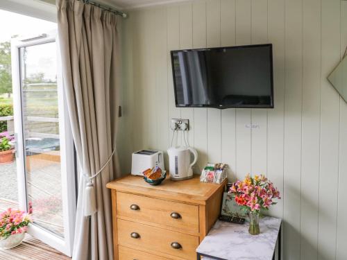 a room with a tv on a wall with a dresser at Alstroemeria in Evesham