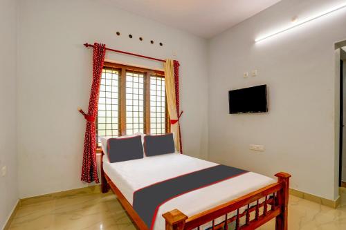 een kleine slaapkamer met een bed en een televisie bij OYO B&B Rooms in Kollam
