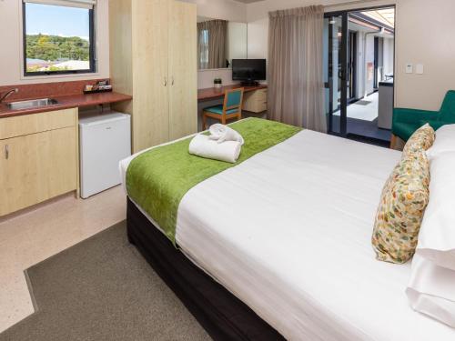 a hotel room with a large bed and a kitchen at Bella Vista Motel Greymouth in Greymouth