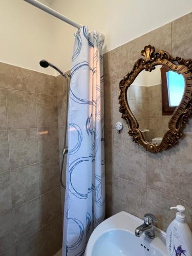 einen Duschvorhang im Bad mit Waschbecken und Spiegel in der Unterkunft MONOLOCALE LA GROTTA in Capilungo