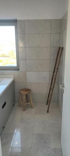 a bathroom with a wooden stool next to a window at Villa celine in Aliki
