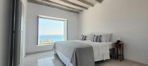 a white bedroom with a bed and a window at Villa celine in Aliki