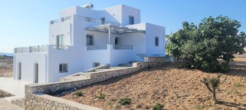 a large white house with a stone wall at Villa celine in Aliki