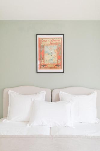 a picture hanging above a bed with white pillows at Les Sarments, Gîte d'exception in Santenay