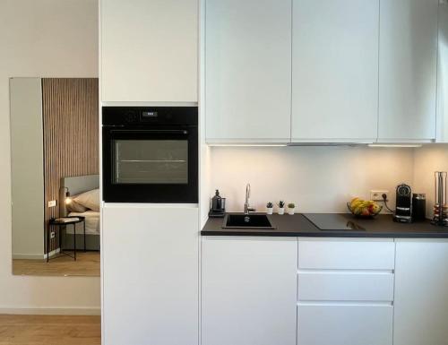 a kitchen with white cabinets and a black microwave at Modernes Apartment im Zentrum von Karlsruhe in Karlsruhe