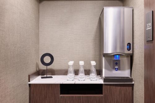 a coffee machine with four glass bottles on a counter at AC Hotel by Marriott San Diego Downtown Gaslamp Quarter in San Diego