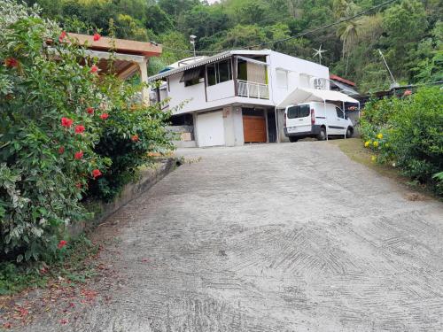 a house with a van parked next to a driveway at La Poulette amazonienne in La Mauny