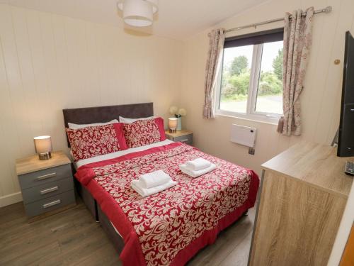 a bedroom with a bed with red sheets and a window at Cotswold View 4 in Evesham