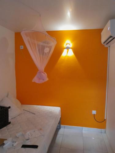 a room with a yellow wall with a light on it at La Poulette amazonienne in La Mauny