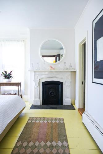 a white room with a fireplace and a mirror at The Waldoboro Inn Room 1 in Waldoboro
