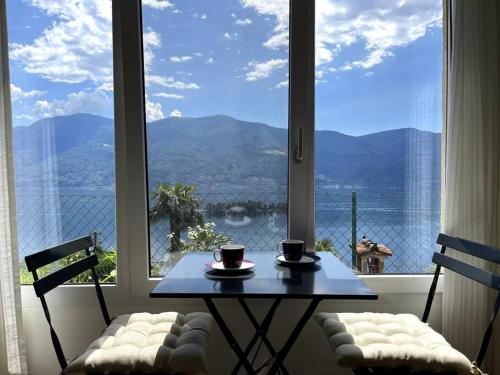 uma mesa e cadeiras em frente a uma janela com vista em Idyllic studio with panoramic views em Ronco sopra Ascona