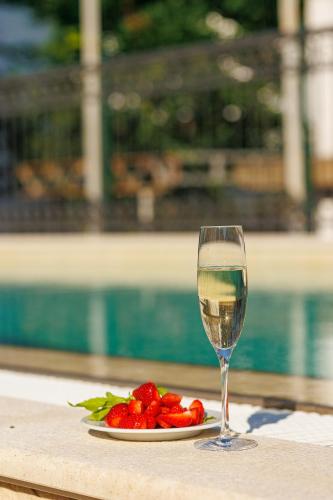 a glass of white wine next to a plate of strawberries at Hotel Kadmo by Aycon in Budva