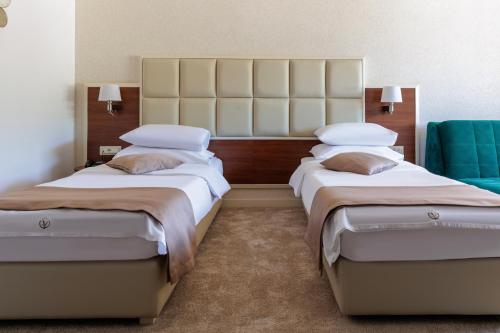 a hotel room with two beds and a blue chair at Hotel Kadmo by Aycon in Budva