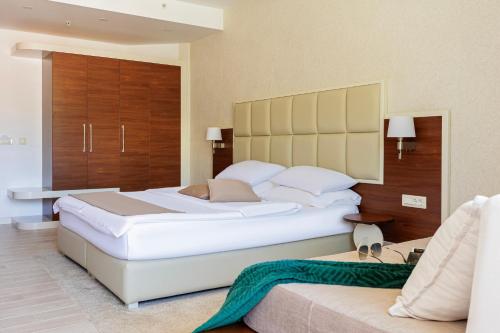 a bedroom with a large white bed and a couch at Hotel Kadmo by Aycon in Budva