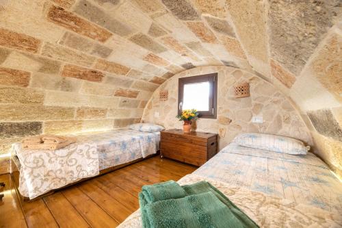 a bedroom with two beds and a stone wall at Trullo, con giardino privato, a pochi mt dal mare in Torre Suda