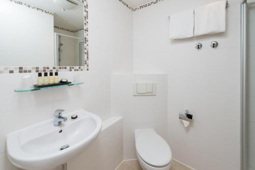a white toilet sitting next to a sink in a bathroom at Hotel Munich Inn - Design Hotel in Munich