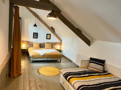 een slaapkamer op zolder met 2 bedden in een kamer bij Le Grenier d'Ouilly au cœur du Pays d'Auge - Gîte avec piscine à 20 min des plages in Ouilly-le-Vicomte