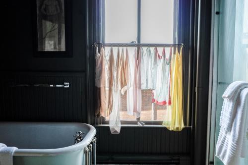 a bathroom with a window with clothes hanging from it at The Waldoboro Inn Room 3 in Waldoboro