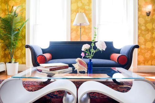 a living room with a blue couch and a glass table at The Waldoboro Inn in Waldoboro