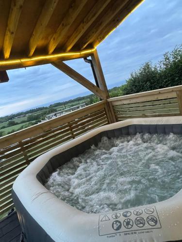 a hot tub on a deck with water in it at Angies Den - quirky cabin with hot tub & views in Llanasa