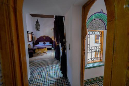 a hallway with a mirror and a room with a bed at Riad Sahraui in Fès