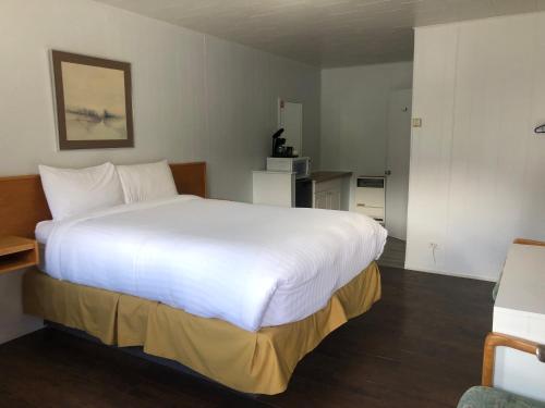 1 dormitorio con 1 cama blanca grande en una habitación en Bavarian Orchard Motel, en Creston