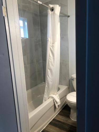 Un baño con bañera blanca y un inodoro. en Bavarian Orchard Motel, en Creston