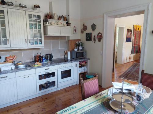 a kitchen with white cabinets and a table with a dining room at Romantik-Villa LebensART in Reichenfels