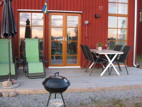 a patio with a table and chairs and a grill at Tällberg, utsikt över Siljan in Leksand