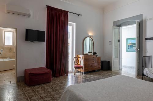 een slaapkamer met een bed, een stoel en een spiegel bij Palazzo Didonna in Rutigliano