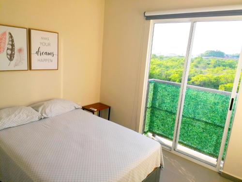 Un dormitorio con una cama y una ventana grande. en Excelente Departamento con Alberca cerca de Playa - Residencial Coto Mareta I, en Mazatlán