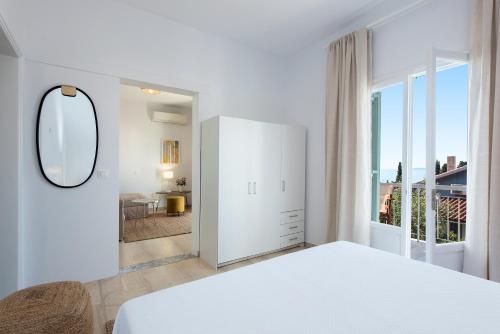 a white bedroom with a bed and a large window at Reana Elegant Apartments in Barbati