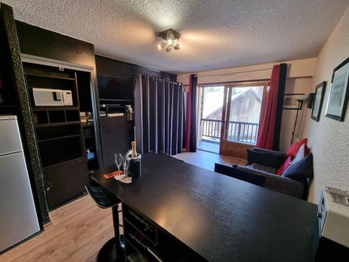 uma cozinha e sala de estar com um balcão preto em La Petite Corneille - a chic and central studio. em Le Monêtier-les-Bains