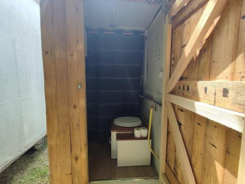 a small bathroom with a toilet in a wooden wall at Tiny House Lapradelle-Puilaurens in Puilaurens