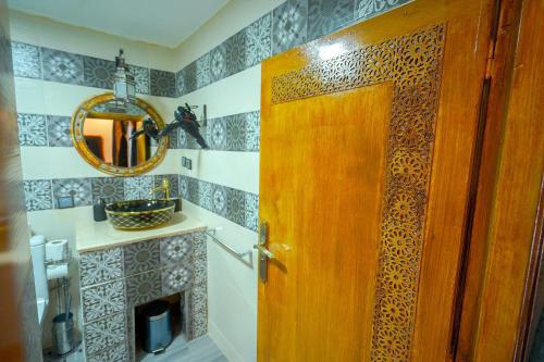 a bathroom with a wooden door and a mirror at Riad Sahraui in Fès