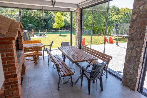 patio con mesa de madera y sillas y parque infantil en Villa UNA LUX en Bihać