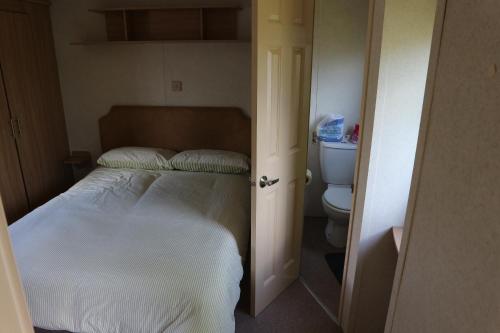 - une petite chambre avec un lit et des toilettes dans l'établissement Holiday home / Caravan, à Felpham