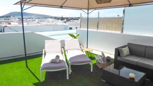 a patio with two chairs and a couch and an umbrella at Apartamentos Mares de Lava - Playa Blanca in Playa Blanca