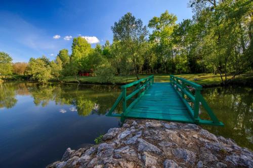 a bridge over a lake with trees in the background at Apartmani CARPE DIEM in Draškovec