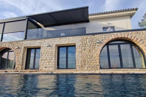 a house with glass windows and a swimming pool at Splendide villa vue mer 180° à 500 m de la plage in Le Lavandou