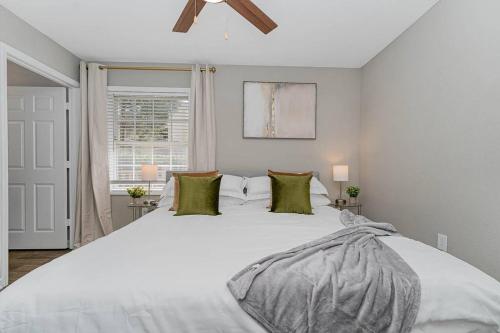 1 dormitorio con 1 cama blanca grande con almohadas verdes en King Beds 2- Smart TVs-Free Parking-Patio en Greensboro